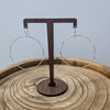 Wooden earring stand with two hoop earrings on a wooden surface.
